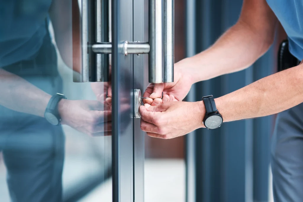 Locksmith using lock picking tools to open the cylinder lock on a commercial glass entry door